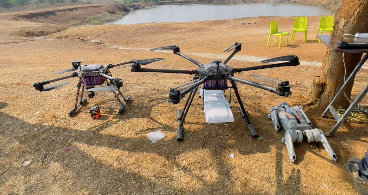 Two professional survey drones and field equipment prepared beside an Indian forest landscape